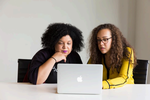 Two professionals working in front of a laptop in an office, comparing top RFI software providers as a guideline for businesses